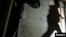 A shadow of a migrant enforcement officer is cast on a makeshift shelter, built by suspected illegal migrant workers, as he tries to break a locked door during a crackdown on illegal migrant workers in Nilai, outside Kuala Lumpur September 1, 2013. 