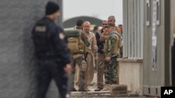 Iraqi Kurdish peshmerga fighters stand at a staging area on the outskirts of Suruc, near the Turkey-Syria border, across from the Syrian town of Kobani, Oct. 30, 2014. 