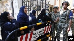 Egyptian women stand in line waiting to cast their votes at the entrance of an election center in Cairo, Egypt, December 15, 2011.