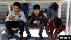 FILE - Boys eat free meals distributed by Namiq Faiq, owner of a charity project in Sulaymaniyah, in Iraqi Kurdistan, March 22, 2019.