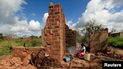 FILE - Ester Thoma cooks at her damaged house in the aftermath of Cyclone Idai, in the village of Cheia, which means "Flood" in Portuguese, near Beira, Mozambique April 1, 2019. 