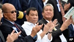 Philippine President Rodrigo Duterte, center, accompanied by Transportation Secretary Arthur Tugade, right, and Defense Secretary Delfin Lorenzana, left, clap their hands at the end of Japan's coast guard drills in Yokohama, Oct. 27, 2016.