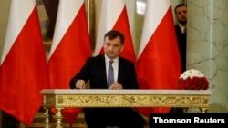 FILE - Zbigniew Ziobro signs documents after being designated as Minister of Justice, at the Presidential Palace in Warsaw, Poland, Nov. 15, 2019.