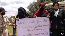 Israeli Arab women hold a sign during a protest ahead of a vote by Israel's parliament on renewing a law that bars Arab citizens of Israel from extending citizenship or even residency to spouses from the occupied West Bank and Gaza.