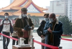 People wear face masks to protect against the spread of the new coronavirus as they visit the Chiang Kai-shek Memorial Hall in Taipei, Taiwan, Thursday, Feb. 27, 2020.