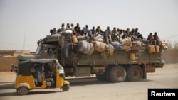 Des migrants assis sur leurs bagages à l’arrière d’un camion qui emprunte une route poussiéreuse dans la ville désertique d'Agadez, au Niger, en direction de la Libye, 25 mai 2015.