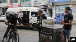 ARCHIVO - El venezolano Maikol Gámez llega en su bicicleta para unirse a sus hermanos Darling y Jhonier para vender café en las calles de Lima, Perú, el 23 de agosto de 2024.