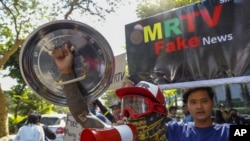 Demonstrators display placards denouncing state and military run TV stations during a protest march against the military coup in Mandalay, Myanmar, on Feb. 11, 2021.