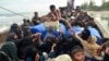 Seorang pria Aceh membagikan makanan kepada pengungsi Rohingya di atas perahu yang terdampar di pantai di Peureulak, Aceh, 29 Januari 2025. (Foto: AP)