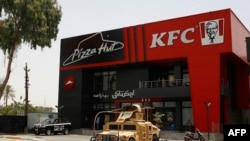 Kendaraan milik pasukan keamanan Irak terparkir di depan Restoran cepat saji KFC dan Pizza Hut di Al-Jadriya, Baghdad, pada 30 Mei 2024. (Foto: AFP/Ahmad Al-Rubaye)