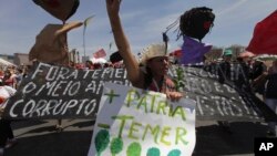 A demonstrator carries a poster written in Portuguese "More Motherland, Less Temer," during a protest after an Independence Day military parade, in Brasilia, Brazil, Sept. 7, 2017. Michel Temer, the president of Brazil, is under investigation for possible obstruction of justice.