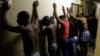 Men stand against a wall as police officers search their room during a raid at an Alexandra township hostel considered a hot spot for anti-immigrant attacks in Johannesburg, South Africa, April 23, 2015.