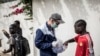 Un travailleur du Village Pilote distribue de l'eau et des sandwichs aux enfants des rues de Dakar, le 10 avril 2020, pendant le confinement.
