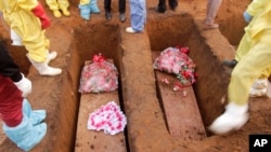 Volunteers bury coffins during a mass funeral for victims of heavy flooding and mudslides in a cemetery in Freetown, Sierra Leone, Aug. 17, 2017. 