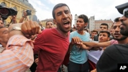 Migrants push and shout as they gather in front of the railway station in Budapest, Hungary, Sept. 3, 2015. 