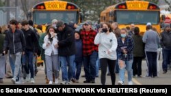 Para orang tua menjauh dari lokasi penembakan bersama anak-anak mereka pasca insiden penembakan di Oxford High School di kota Oxford, Michigan, Selasa (30/11). 