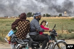 FILE - Members of a Syrian family use a motorcycle to flee the countryside of the northeastern Syrian town of Ras al-Ain on the Turkish border, toward the west to the town of Tal Tamr, Oct. 19, 2019.