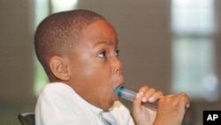FILE - Alexander McBride, 8, who has asthma, exhales into a peak flow meter in Severna Park, Maryland, Aug. 13, 1998.