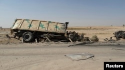 FILE - A burnt vehicle belonging to the Iraqi security forces is seen on the outskirt of Haditha, northwest of Baghdad August 26, 2014. On Monday, Jan. 4, 2016, IS militants attacked Iraqi troops and allied tribal fighters outside Haditha, killing at least 11 and wounding dozens.