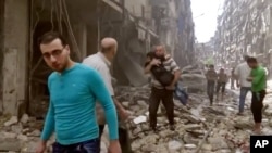 In this image made from video and posted online from Validated UGC, a man carries a child after airstrikes hit Aleppo, Syria, April 28, 2016.