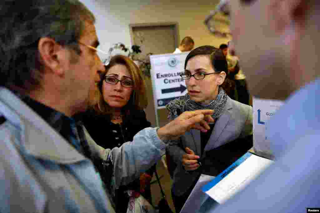 Hossein Khoshbakhty, left, speaks with attorney Talia Inlender about his Iranian family members effected by the travel ban as Homa Homaei, second from left, looks on outside the U.S. Customs and Border Protection office at Los Angeles International Airport (LAX) in Los Angeles, Jan. 28, 2017.