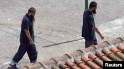 FILE - Two Chinese Uighurs, released from Guantanamo in 2006, are seen following their arrival at a resettlement center in Tirana, Albania.