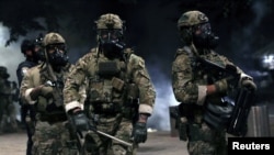 Petugas penegak hukum federal terlihat siaga penuh selama berlangsungnya aksi demo menentang kehadiran petugas penegak hukum federal dan ketidaksetaraan ras di Portland, Oregon, AS, 21 Juli 2020. (REUTERS / Caitlin Ochs)