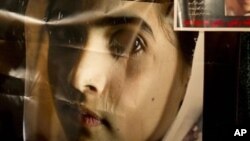 Pakistani protesters hold poster of 14-year-old schoolgirl Malala Yousufzai, who was shot Tuesday by the Taliban for speaking out in support of education for women, Karachi, Oct. 11, 2012.