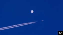Sebuiah jet tempur terbang melintasi balon yang berada di atas Samudra Atlantik, di lepas pantai South Carolina, pada 4 Februari 2023. (Foto: Chad Fish via AP)
