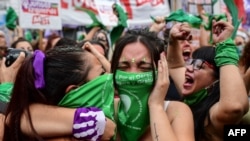 Demonstrators celebrate with green headscarves - the symbol of abortion rights activists - outside the Argentine Congress in Buenos Aires on December 11, 2020, after legislators passed a bill to legalize abortion.
