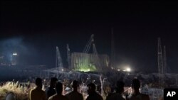 People look at the scene of Tuesday's explosion that hit the seaport of Beirut, Lebanon, Aug. 7, 2020.