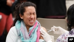 A women reacts to getting an influenza vaccine shot at Eastfield College in Mesquite, Texas, Jan. 23, 2020.