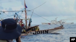 Kapal Garda Pantai Tiongkok melintas di belakang perahu milik aktivis dan sukarelawan dari koalisi non-pemerintah Atin Ito, yang berarti "Ini Milik Kita" dalam bahasa Tagalog, di Laut China Selatan pada Kamis, 16 Mei 2024. (Foto: via AP)