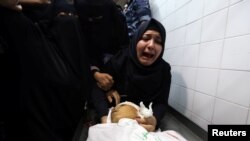 FILE - The aunt of Palestinian boy, who was killed by Israeli forces during a protest at the Israel-Gaza border, reacts next to his body at a hospital morgue in the southern Gaza Strip, June 29, 2018. 