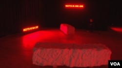 Prostorija sa teškim kamenovima koji izgledaju kao grobnice i digitalnim satovima koji mere vreme od kada su pojedine osobe nestale na izložbi "Bolje grob nego da se ne zna" u Prištini (Foto: VOA)