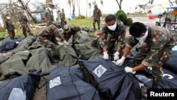 Soldiers zip up body bags after families have identified their relatives who perished during super Typhoon Haiyan in Tacloban city, central Philippines, Nov. 13, 2013.
