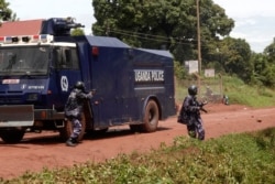 FILE - A police officer holds to shoot tear gas toward supporters of Ugandan politician Robert Kyagulanyi, known as Bobi Wine, at Busabala, April 22, 2019. Security forces raided offices of Bobi Wine's National Unity Platform party Oct. 14, 2020.