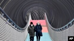People wear protective face masks due to the coronavirus pandemic, as they walk over a bridge during the lockdown in Oberhausen, Germany, Monday, Jan. 11, 2021. 