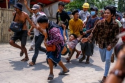 Protesters carry an injured man after riot policemen and soldiers shot rubber bullets during a crackdown on demonstrations in Yangon, Myanmar, March 14, 2021.