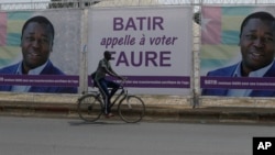 Un homme passe à vélo devant les affiches électorales du président sortant du Togo, Faure Gnassingbé, à Lomé, le 21 février 2020. (AP)