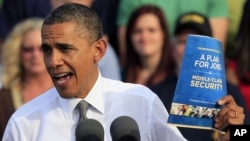 President Barack Obama holds up a copy of jobs plan during a joint campaign appearance with Vice President Joe Biden (not seen) at Triangle Park in Dayton, Ohio, October 23, 2012.