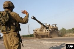 Izraelski vojnik usmerava kretane samohodne haubice, nedaleko od južnog grada Aškelona, 8. oktobra 2023.