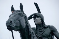 A statue of a Sioux Indian scout wears a face mask as it stands on a bluff overlooking Kansas City, Mo., March 26, 2020.