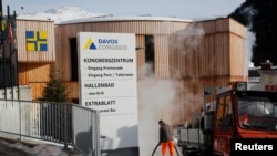 FILE - A worker uses steam to remove ice from a footpath in front of one of the venues of the World Economic Forum (WEF) in Davos, Switzerland, Jan. 13, 2020.