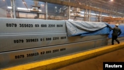 An employee removes a covering of 13-meter aluminium ingots weighing 34 tons (74,957 pounds) at the foundry shop of the Rusal Krasnoyarsk aluminium smelter in Krasnoyarsk, Siberia, July 27, 2016. 