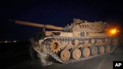 A Turkish army tank is driven to its new position on the Turkish side of the border between Turkey and Syria, in Sanliurfa province, southeastern Turkey, Oct. 8, 2019. 