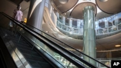 2022年5月21日，一名戴着口罩的女子在北京一家空空荡荡的商场里的自动扶梯上。