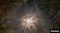 Orang-orang berdiri di sekitar kawah yang terbentuk akibat serangan rudal Rusia, di tengah serangan Rusia ke Ukraina, di desa Buda-Babynetska, di luar Bucha, dekat Kyiv, Ukraina 15 Februari 2024. (REUTERS/Thomas Peter)