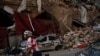 A cyclist rides past destroyed buildings and cars in a neighborhood near the site of last week's explosion that hit the seaport of Beirut, Lebanon, Aug. 11, 2020.