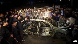 Palestinians surround the wreckage of a vehicle following an Israeli airstrike that killed three of Hamas militants near Deir Al Balah, central Gaza Strip, April 2, 2011
